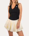 Front three-quarter close-up of cream pleated tennis skirt with high-waist band