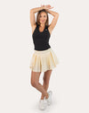 Full-body front view wearing a cream pleated tennis skirt with high-waist band