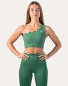 Front close-up of emerald green gym set top highlighting the scalloped one-shoulder neckline