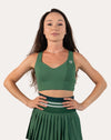 Front view of the forest green longline sports bra with hands on hips; V-neck and supportive band