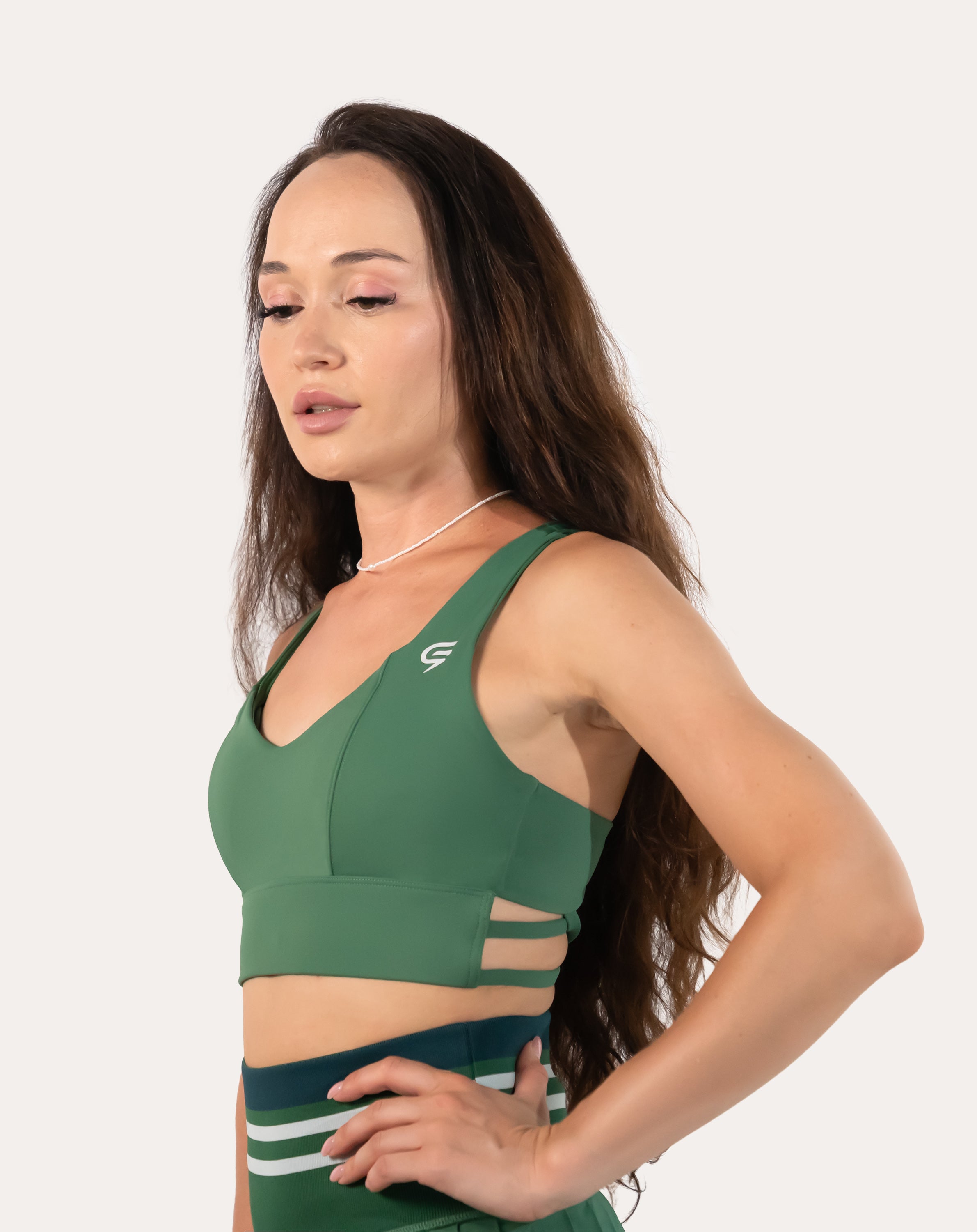Forest green longline sports bra, front three-quarter close-up showing V-neck and side cutout straps