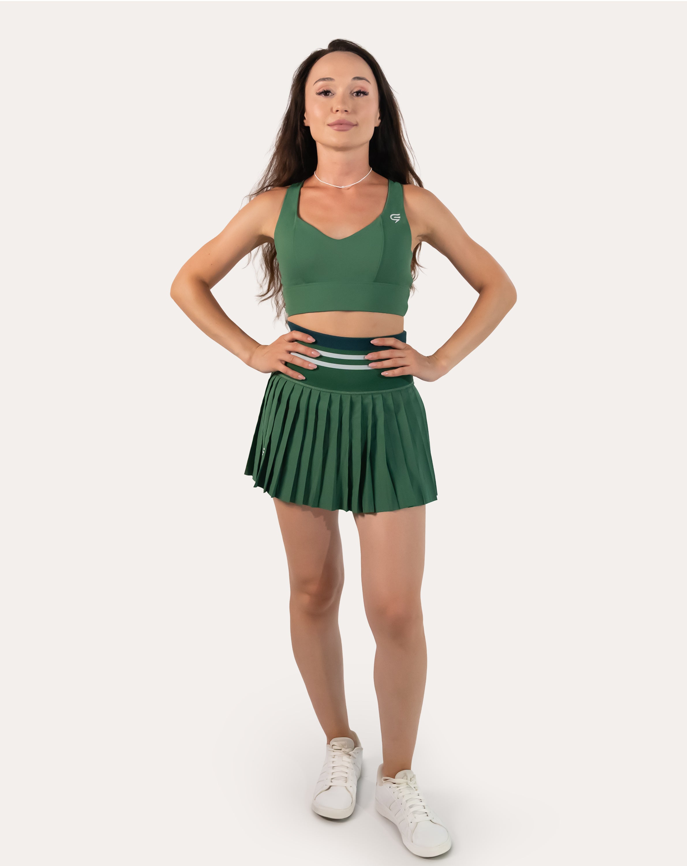 Full-body front view of forest green pleated tennis skirt with high-waist striped band