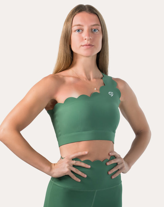 Straight front view of green sports bra with scalloped one-shoulder strap and smooth finish