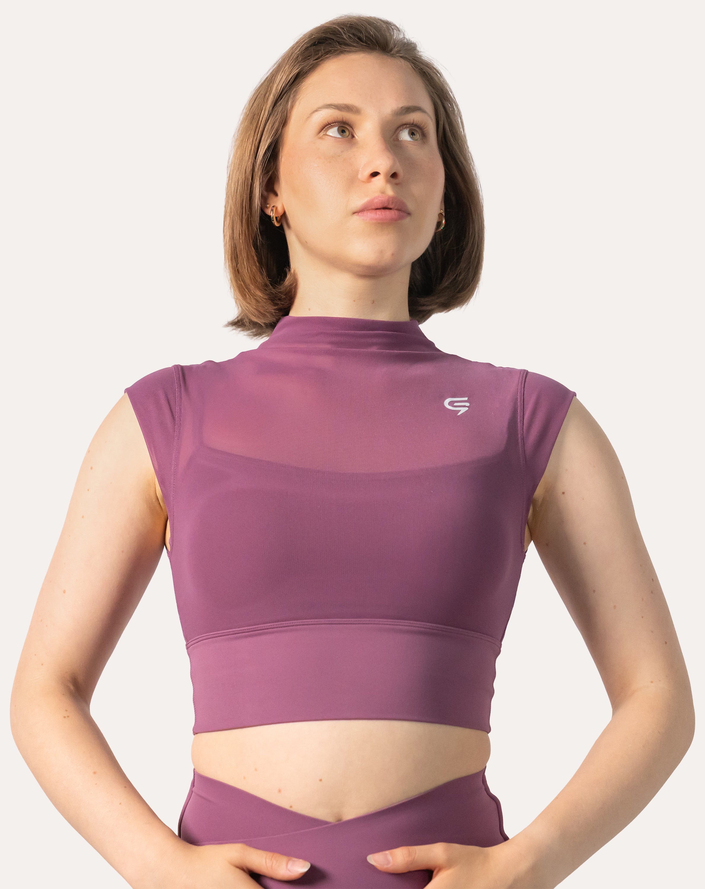 Close-up of the high neck gym top in purple highlighting the mock neck, cap sleeves and sculpting crop silhouette