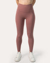 Front view of women’s high-waisted leggings in rose-clay pink; buttery-soft, ankle-length fit styled with white sneakers