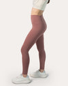 Side stretch pose showing flexible four-way stretch and supportive high-rise band on rose-clay high-waisted leggings