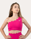 Front view of hot pink sports bra with scalloped one-shoulder strap and wide underband