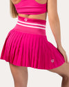 Left back three-quarter view of hot pink tennis skirt showing pleated mini hem and striped high waist