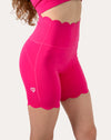 Front three-quarter close-up of hot pink yoga shorts with scalloped high waist and hem