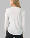 Back close-up of white ladies long sleeve gym top highlighting sheer knit and curved hem