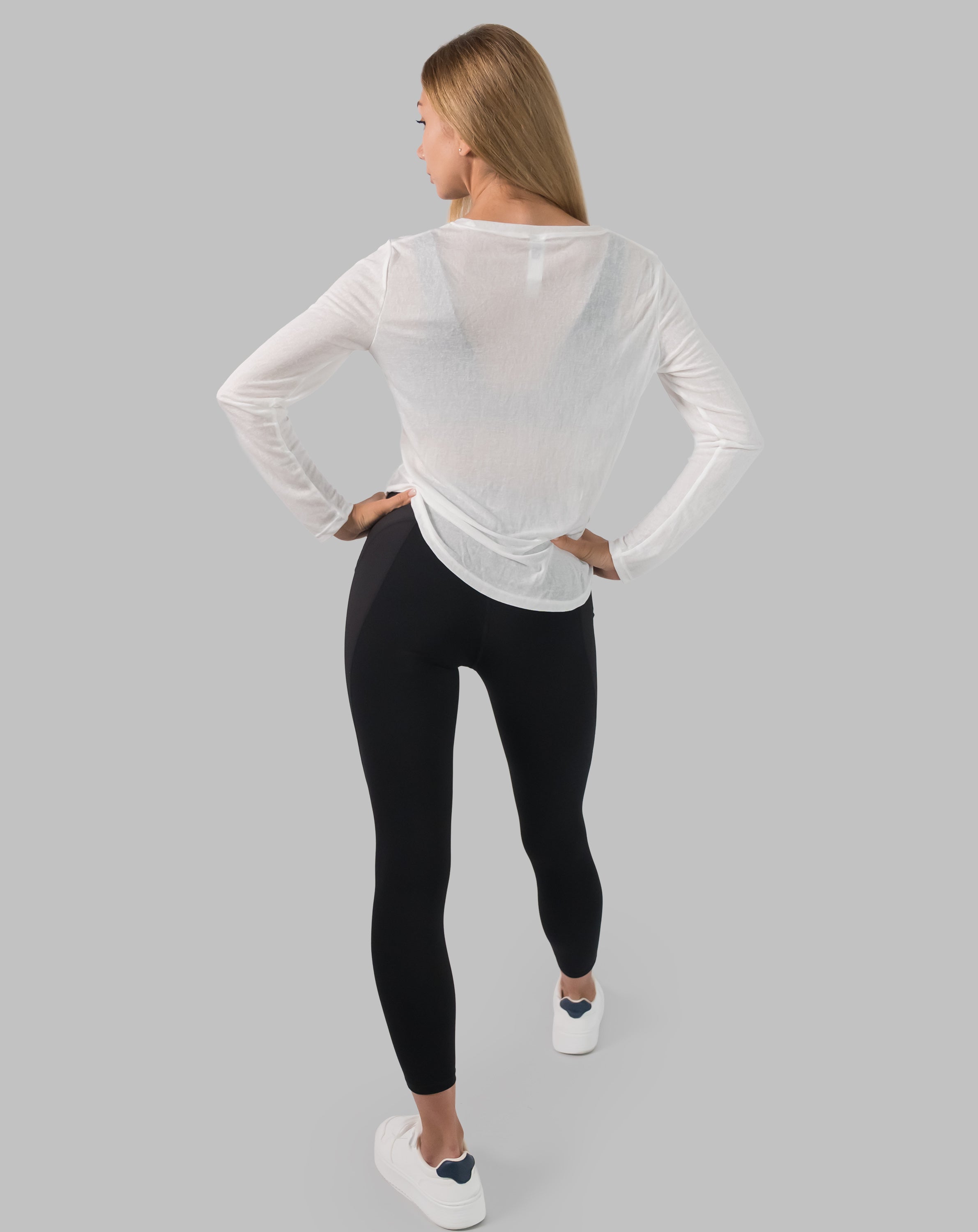 Back full-length view of white ladies long sleeve gym top showing relaxed longline fit