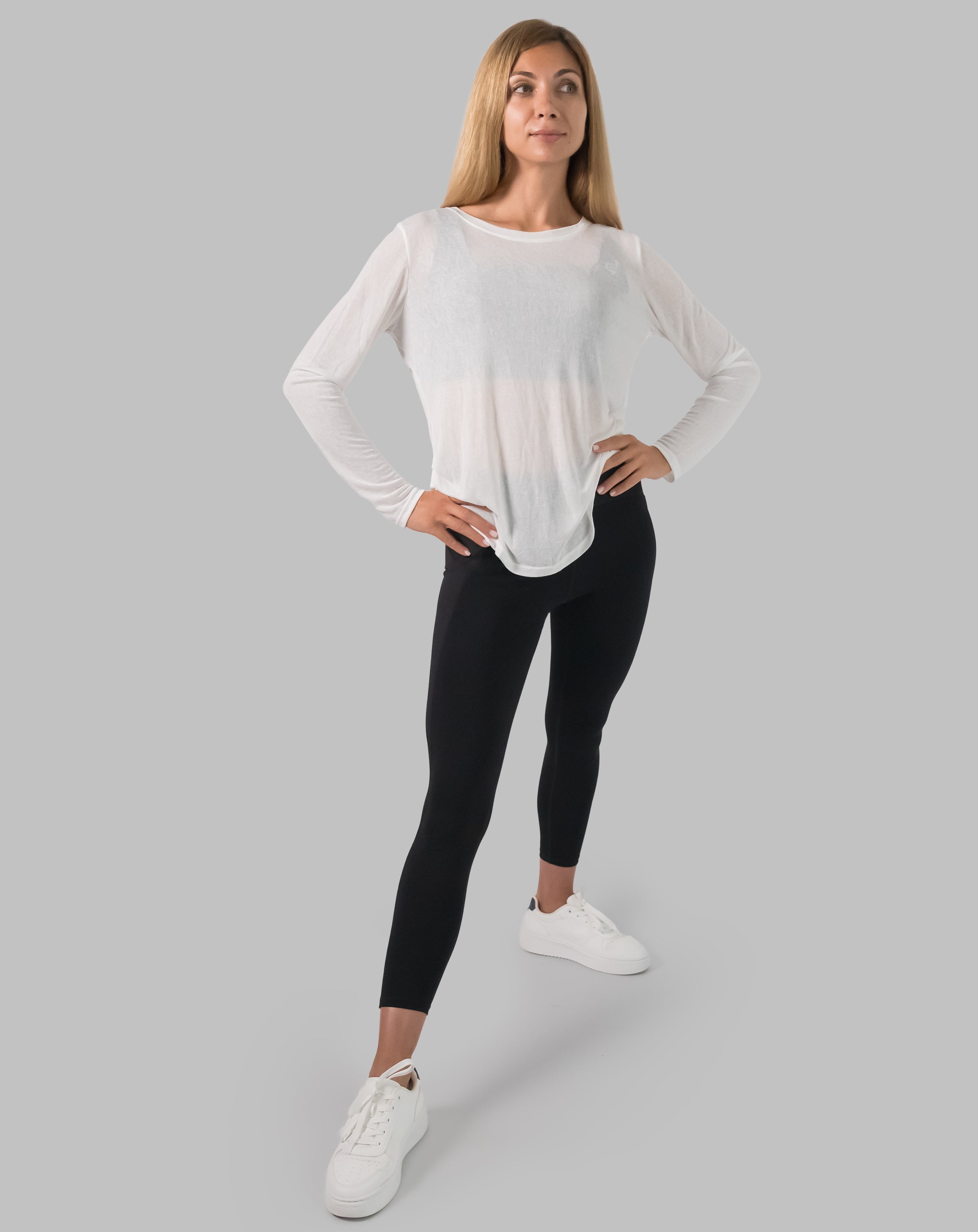Front full-length view of white ladies long sleeve gym top with curved hem over leggings