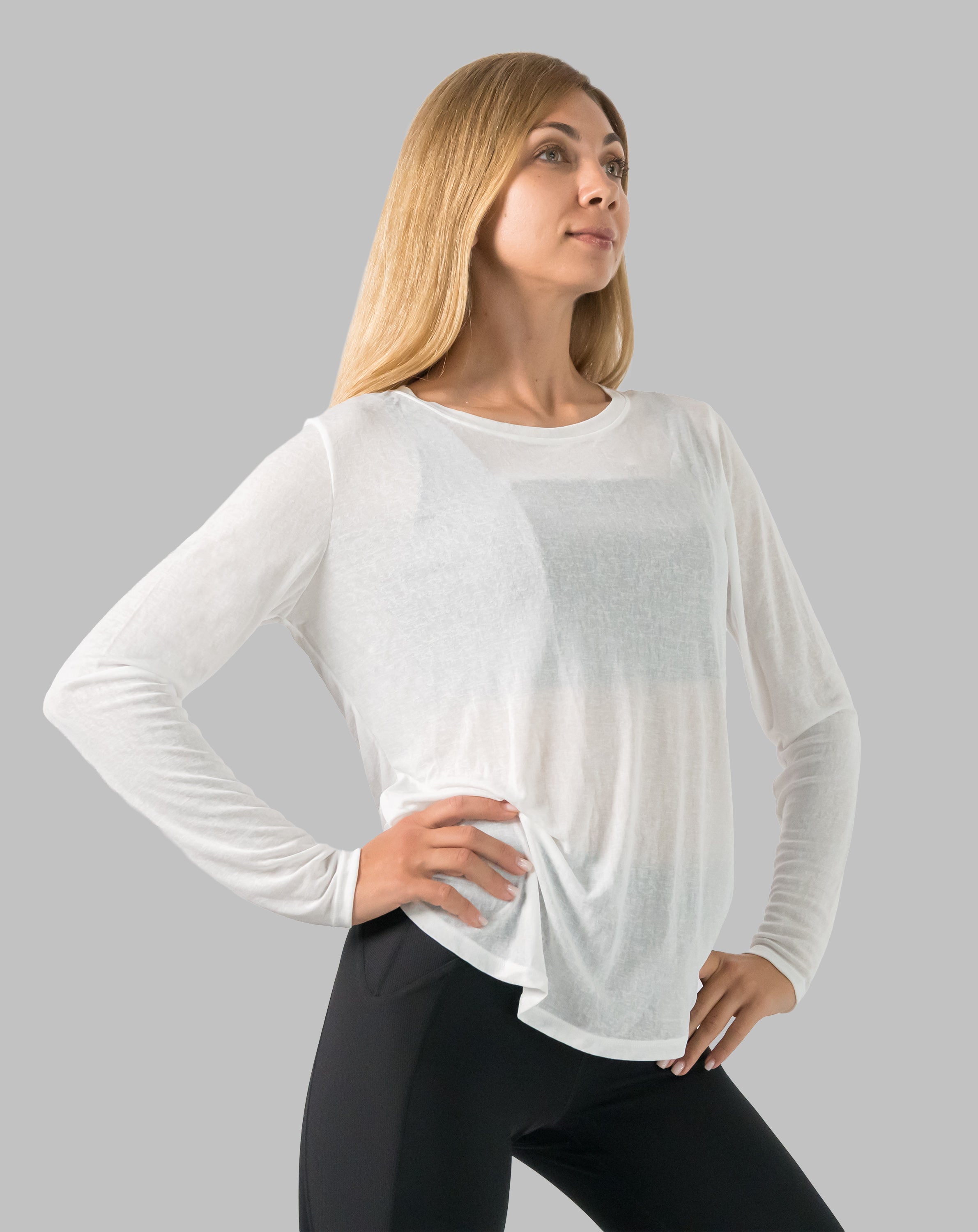 Side profile of white ladies long sleeve gym top with semi-sheer fabric and relaxed drape