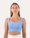Front view of light blue square neck sports bra with rib side panels and firm underband