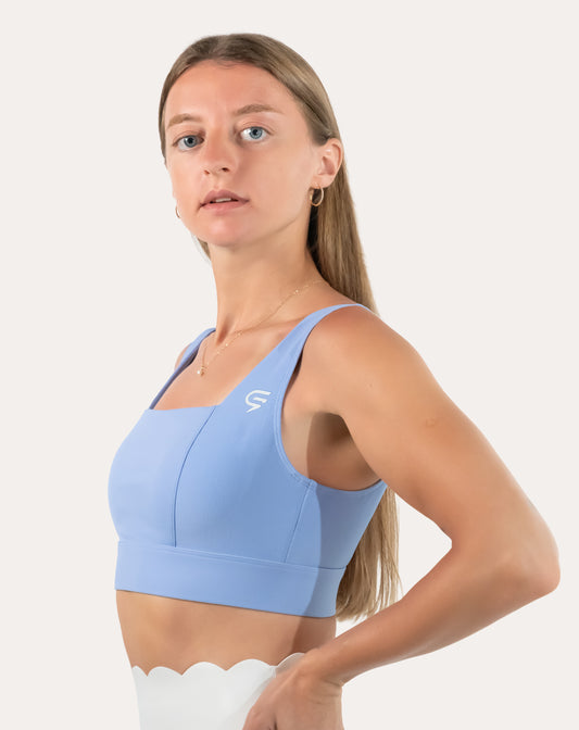 Front three-quarter view of light blue square neck sports bra with wide straps