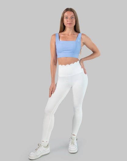 Full-body front view wearing a light blue square neck sports bra with white leggings