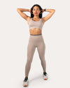 Front view with arms raised showing the light grey gym set’s scoop bra and smooth high-waist leggings