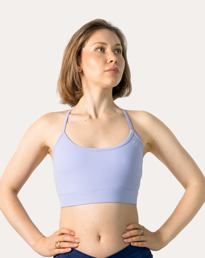 Mid-length front of lilac racerback sports bra with hands on hips; scoop neck and wide band