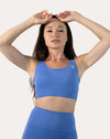 Close-up of bra from sapphire blue matching gym set; arms raised to show neckline and coverage