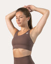 Mocha running bra, front view with arms raised to show strap placement and smooth scoop front