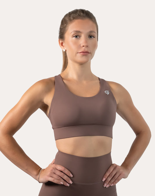 Mocha running bra, front close-up with scoop neck and wide underband; hands on hips