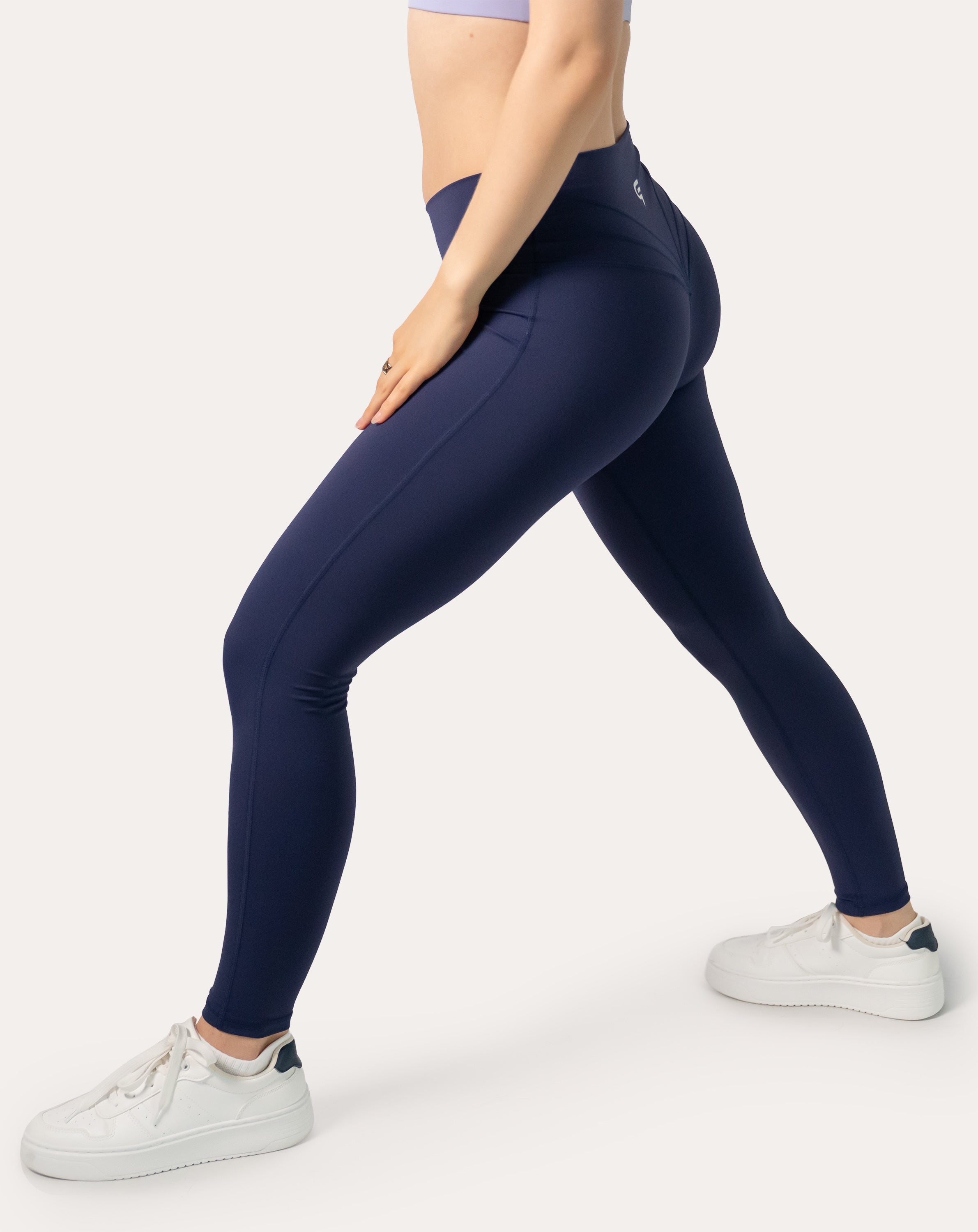 Navy scrunch bum leggings with crossover V-waist; right three quarter view in a step stance