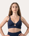 Navy sports bra front mid-length with hands on hips; V-neck and double straps shown