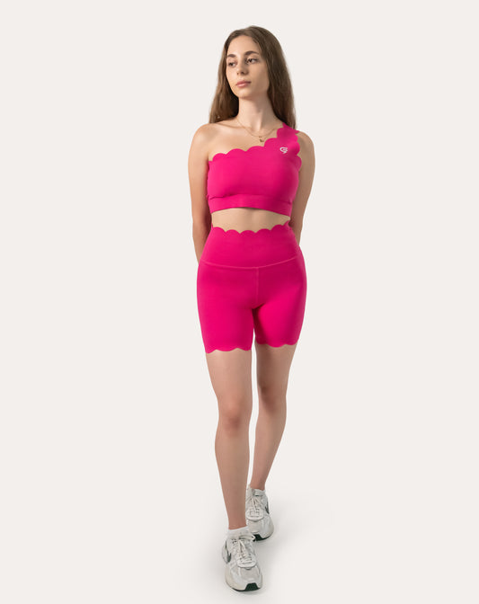 Front view of neon pink gym set with one-shoulder longline bra and high-waist biker shorts