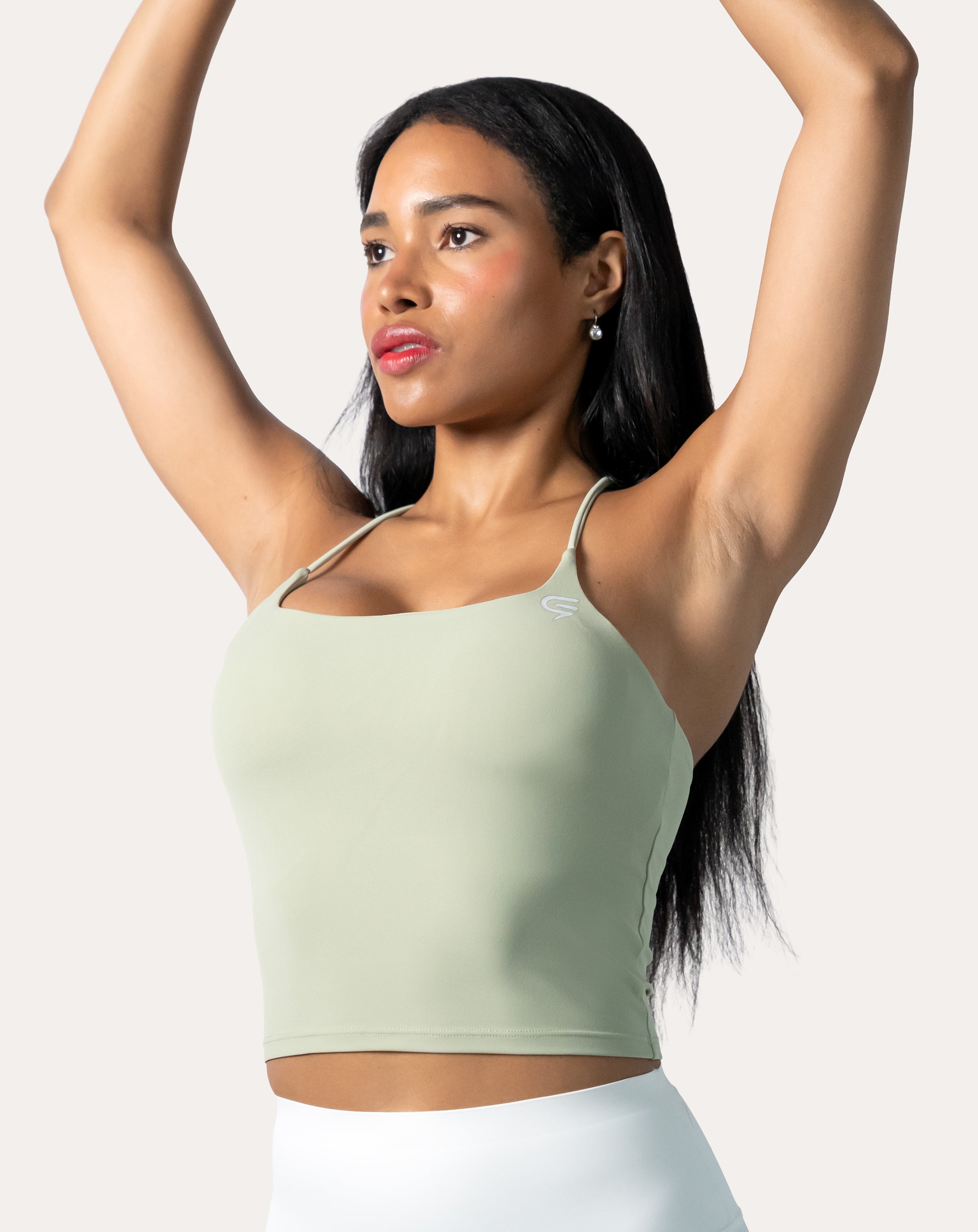 Sage green open back gym top, front view with arms raised to show strap mobility and crop