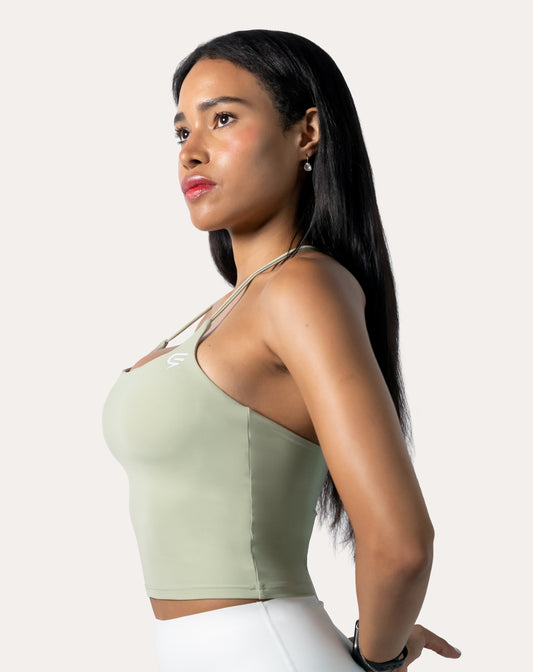 Sage green open back gym top in side profile showing cropped hem and minimal seams