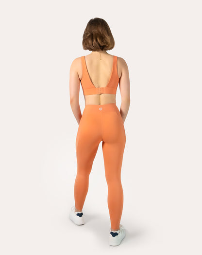 Back full-length view of orange gym set showing bra back closure and high-waist leggings