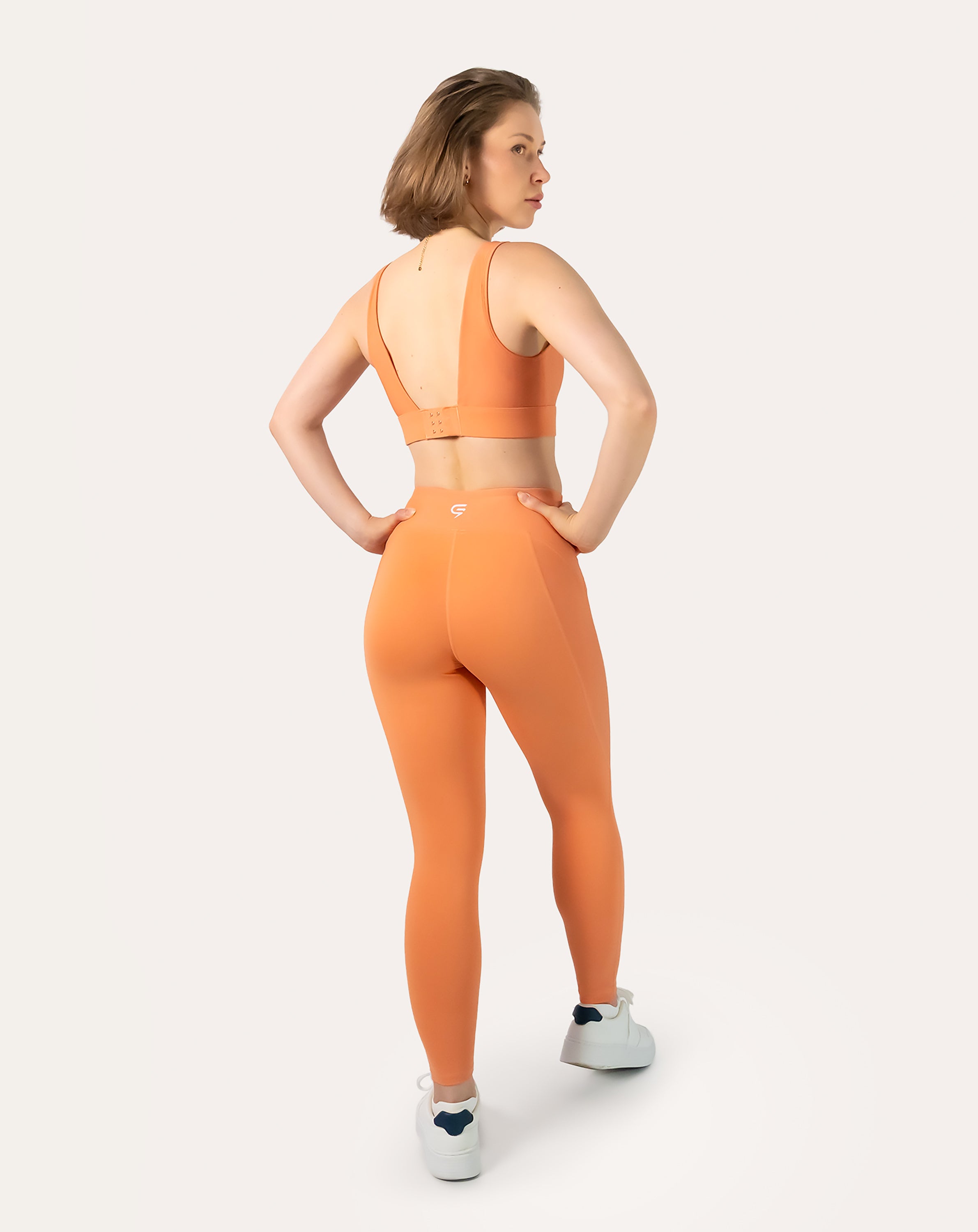 Three-quarter back view of orange gym set highlighting bra back closure and wide waistband