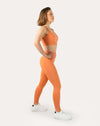 Side profile of orange gym set showing square-neck bra and sculpting high-waist leggings