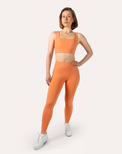 Full-body front view wearing an orange square neck sports bra with matching bottoms