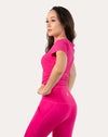 Three-quarter side view of hot pink women’s gym top showing fitted ribbed fabric