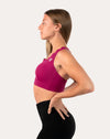 Back three-quarter left view showing crisscross straps on pink sports bra in magenta