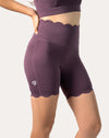 Side close-up of plum high-rise biker shorts from the one-shoulder gym set with smooth seams and logo