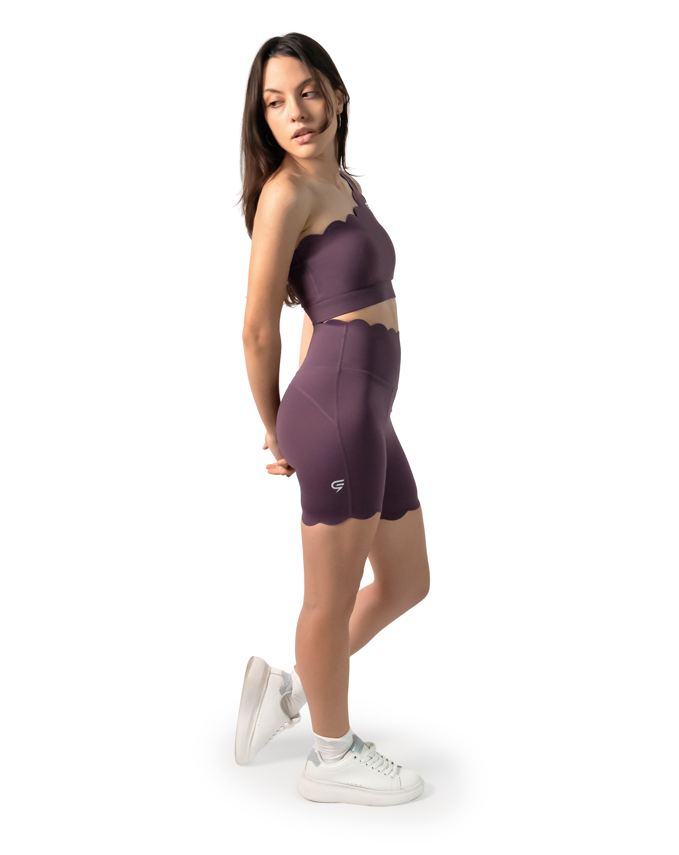 3/4 front pose of the plum one-shoulder gym set; scallop neckline on the longline bra.