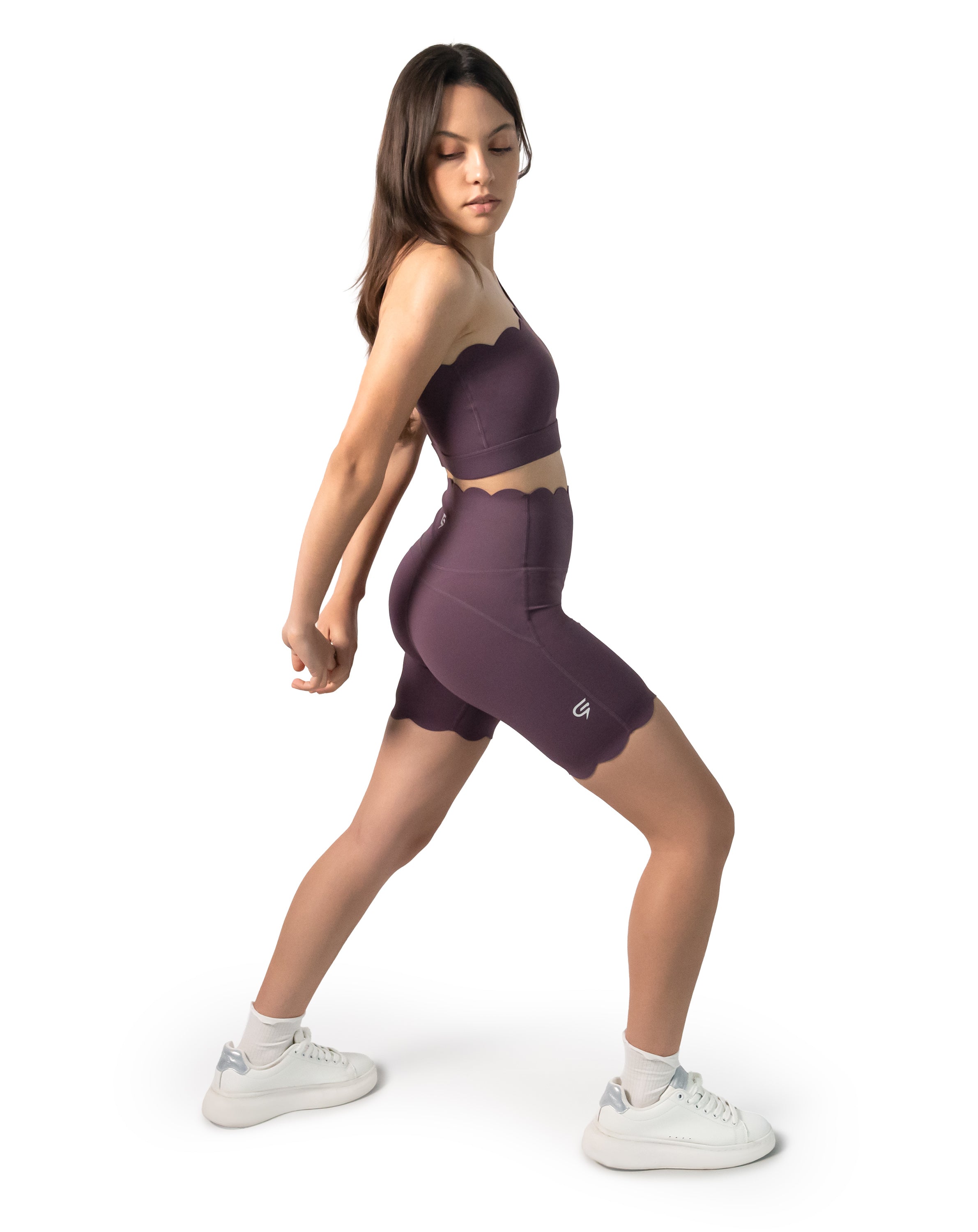3/4 side lunge showing fit of the plum one-shoulder gym set and supportive biker shorts