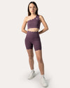 Front view of plum one-shoulder gym set with longline bra and high-rise scallop biker shorts