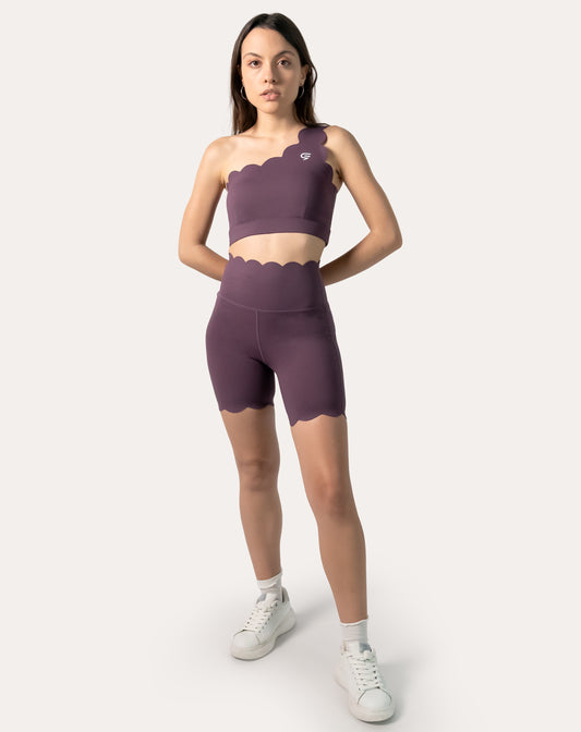 Front view of plum one-shoulder gym set with longline bra and high-rise scallop biker shorts