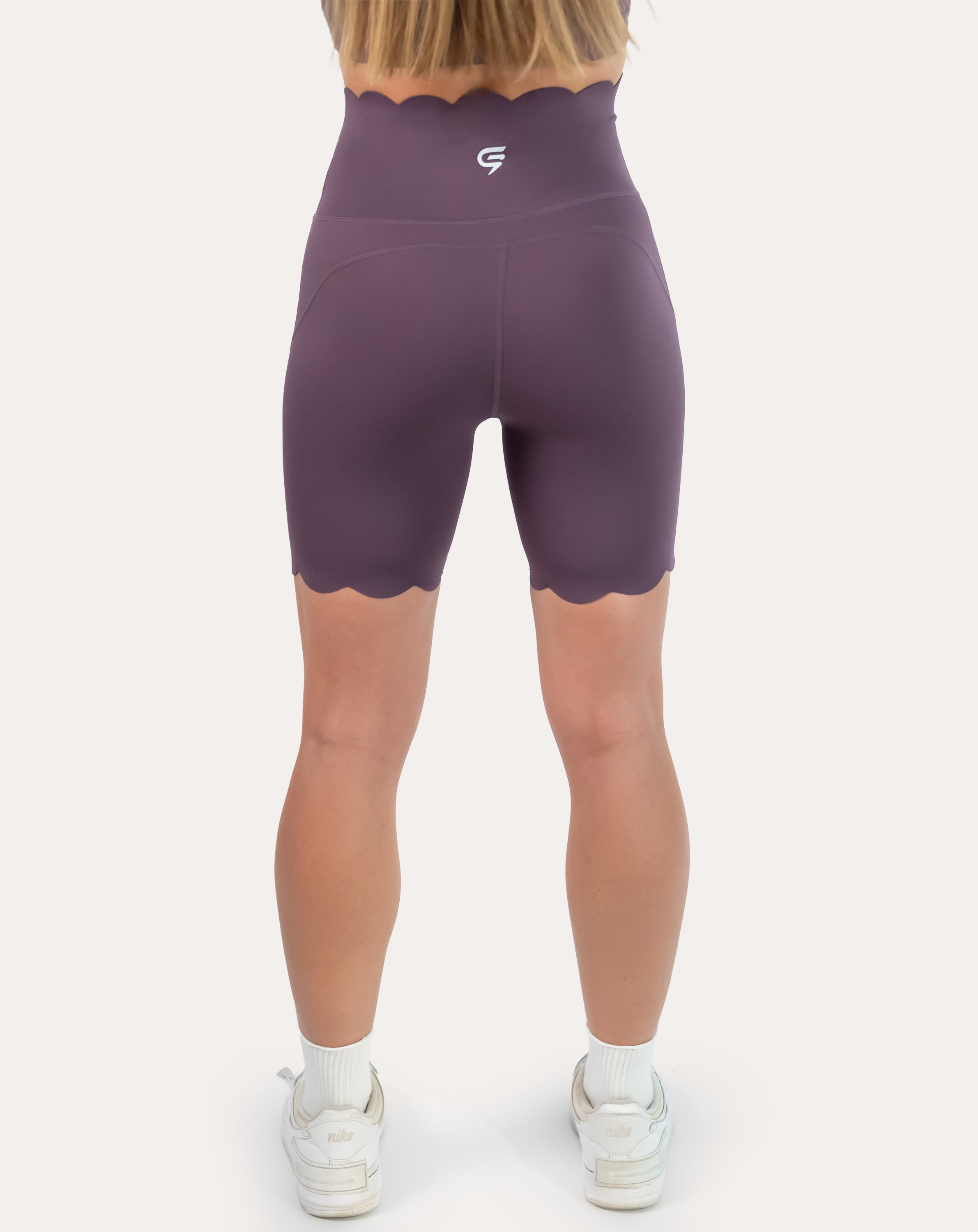 Back view of plum gym shorts with scalloped hem and supportive high waist