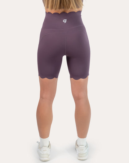 Back view of plum gym shorts with scalloped hem and supportive high waist