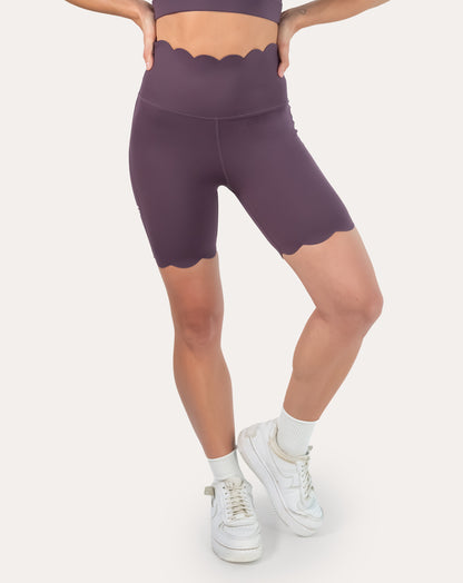 Right front three-quarter view of plum gym shorts with scalloped hem and high waist