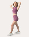 3/4 side pose with arm raised, showing fit of plum gym shorts set and stay-put waistband