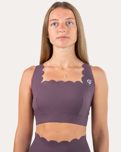 Front view of purple cross back sports bra with scalloped neckline and wide underband