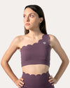 Straight front view of purple sports bra with scalloped one-shoulder neckline and wide underband
