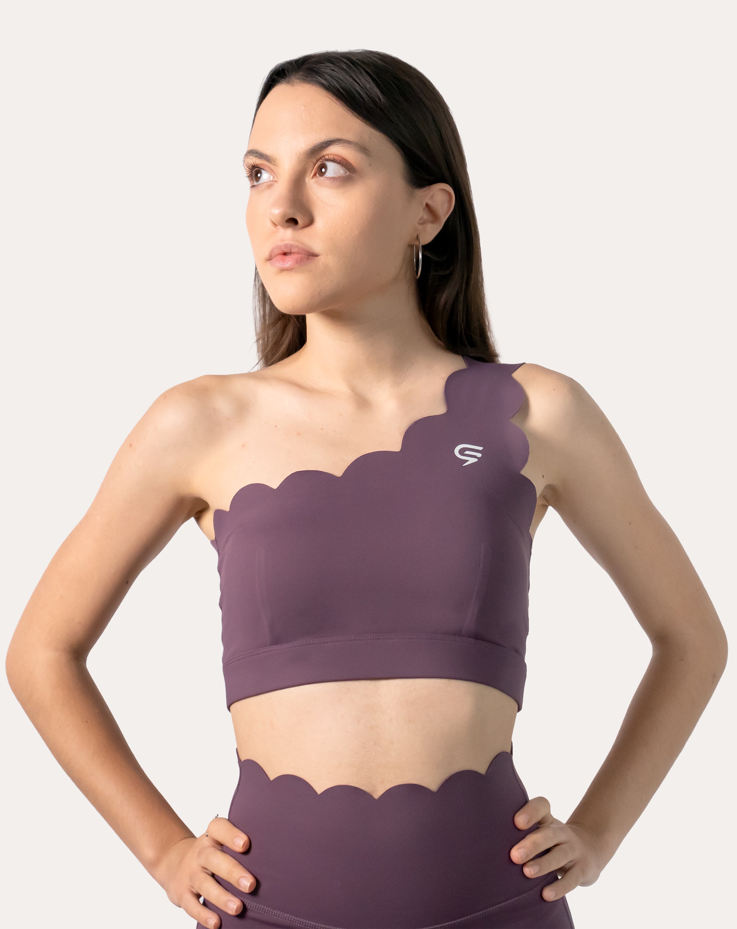 Straight front view of purple sports bra with scalloped one-shoulder neckline and wide underband