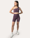 Full-body view of model wearing purple sports bra with matching shorts