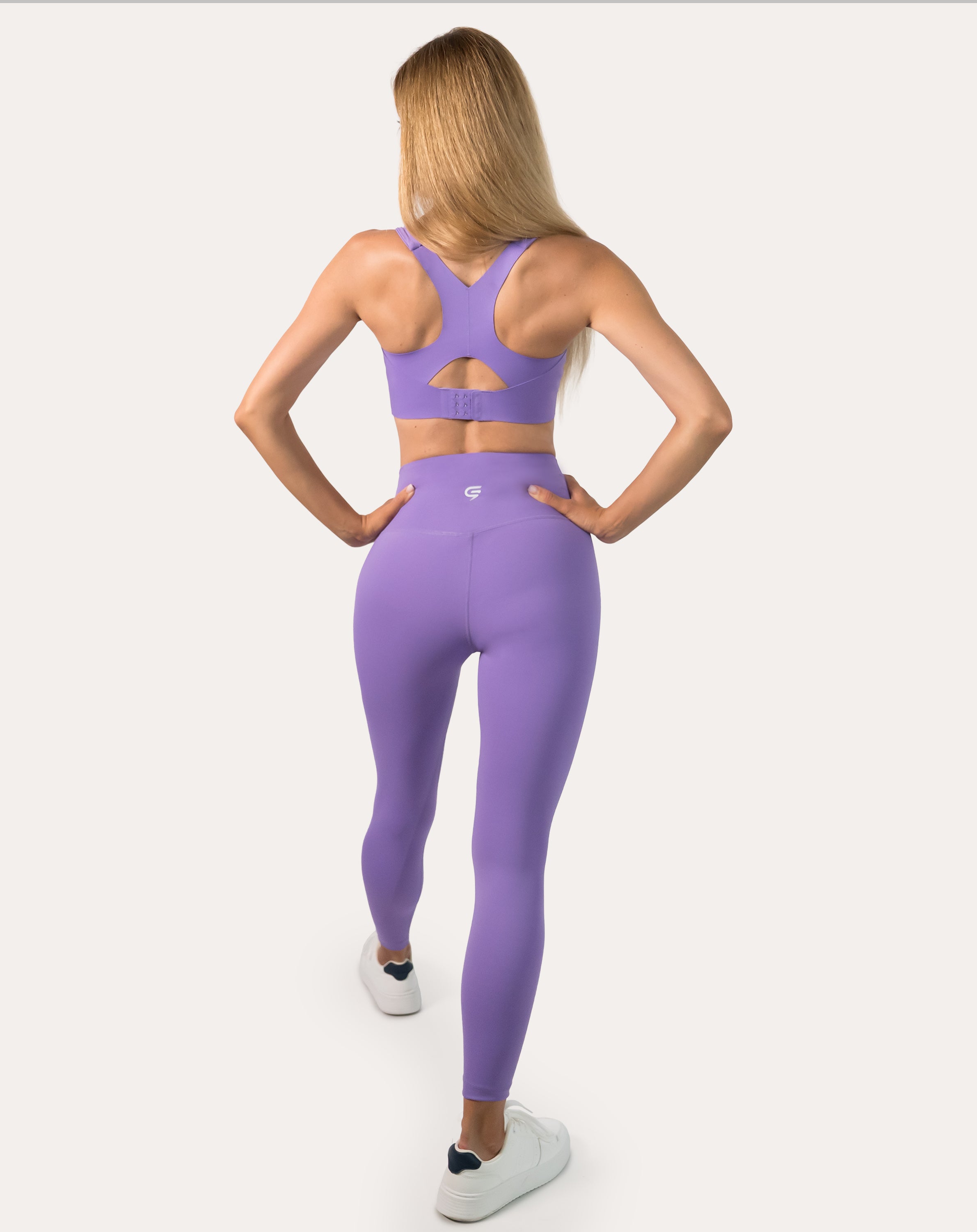 Full-length back view of purple sports bra showing racerback straps and longline band in stride